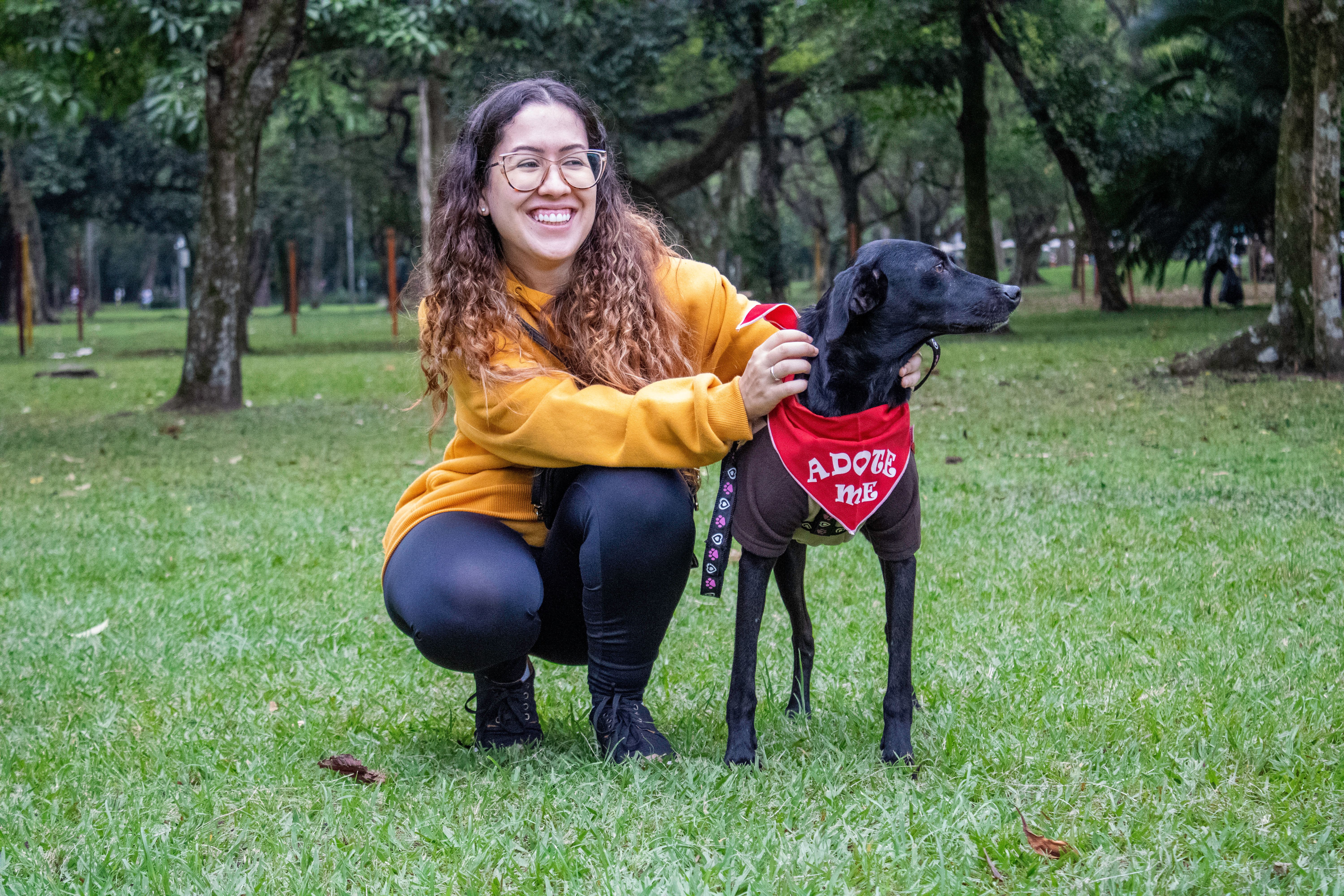 Une femme souriante avec un chien adoptable dans un parc